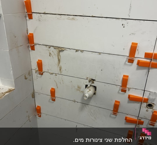 קיר עם אריחים וכלי עבודה כתומים